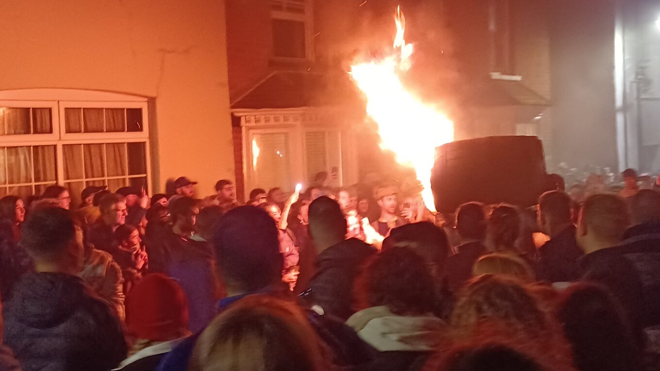 A flaming tar barrel being carried through crowds of people on Paternoster Row, Ottery St. Mary, 5th November 2025.